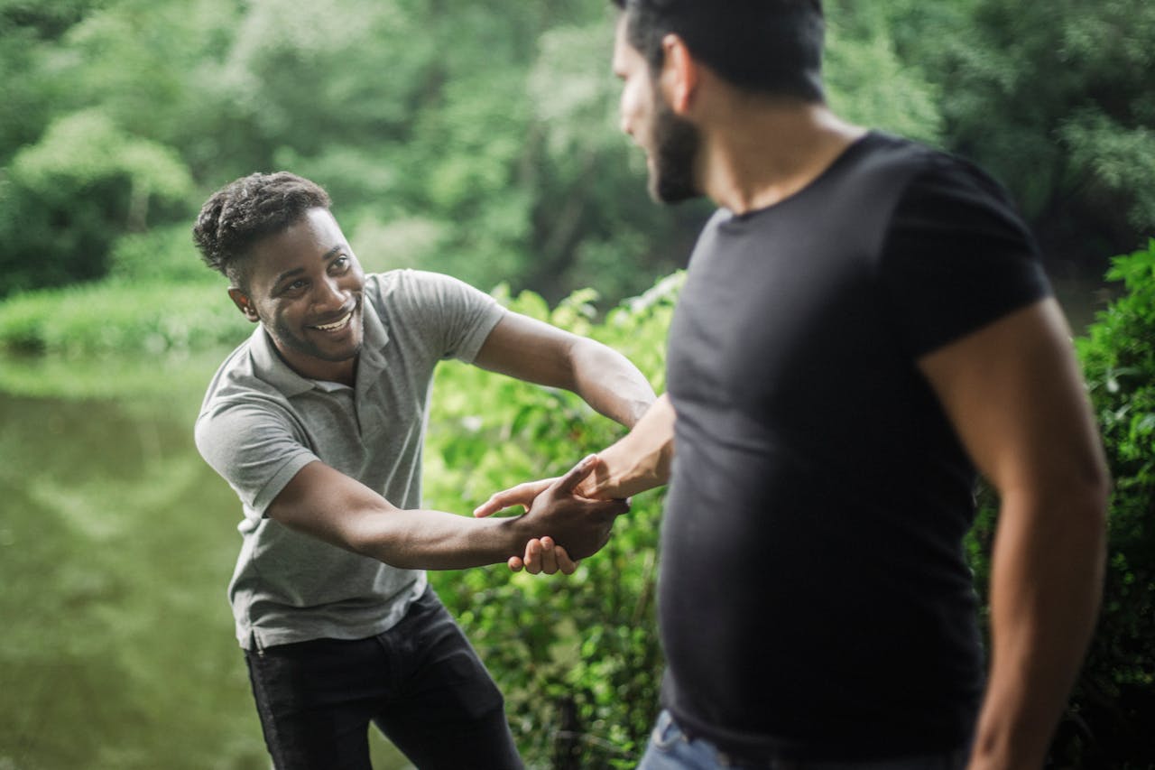Photo of a Man in a Gray Shirt Smiling at a Man in a Black Shirt